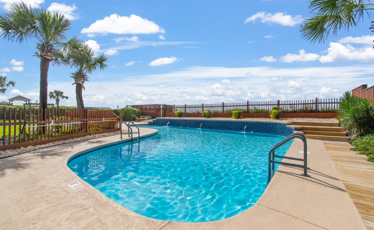 Community pool with palm trees and ocean views